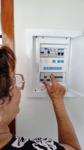 A woman interacting with an electrical control panel inside a house, showing hands-on operation.