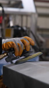 Close-up of a worker using a pneumatic sander for metal surface finishing in an Istanbul workshop.